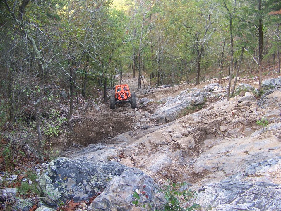 Orange off-road vehicle on a rocky, wooded trail