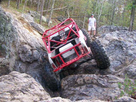 2001 Dodge 1500 - A heavily modified off-road vehicle navigates a challenging rocky terrain, with a spectator observing the action.