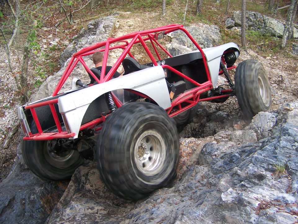 Off-road buggy with red roll cage climbing rocks