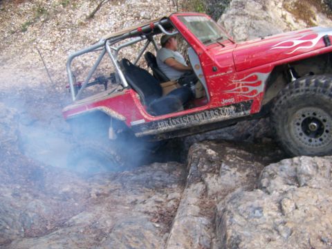 2001 Dodge 1500 - A red Jeep Wrangler navigates a rocky off-road course, with smoke billowing from its tires.