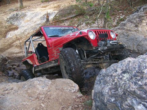 2001 Dodge 1500 - This red Jeep Wrangler is tackling a challenging rocky terrain, demonstrating its off-road capabilities.