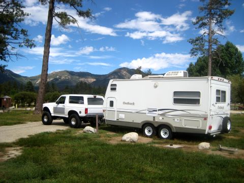 1996 Ford Bronco - A white Ford Bronco tows a travel trailer at a campsite with mountains in the background.