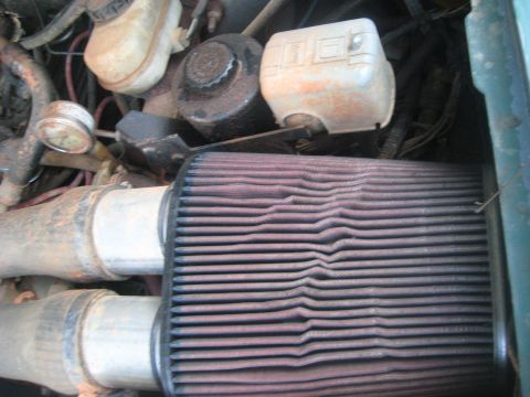 1990 Ford Bronco - Close-up view of an engine bay, focusing on the air intake system and various fluid containers.