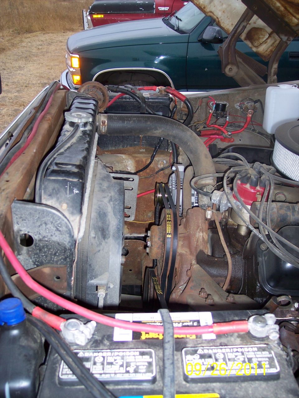 Older Ford V8 truck engine bay with red distributor cap, chrome air cleaner and heavy red battery cable