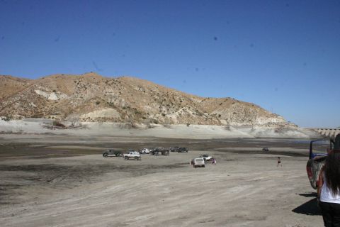1991 Ford Bronco - A group of off-road vehicles are gathered in a wide, dry landscape under a clear blue sky.