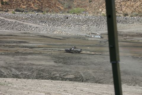 1991 Ford Bronco - A gray Ford Bronco navigates a muddy, dry lakebed under a clear sky.