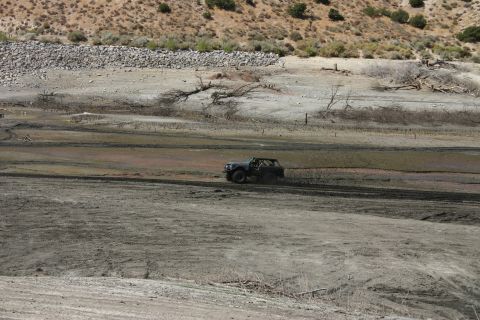 1991 Ford Bronco - A vehicle navigates a dry, muddy terrain under a bright, arid sky.
