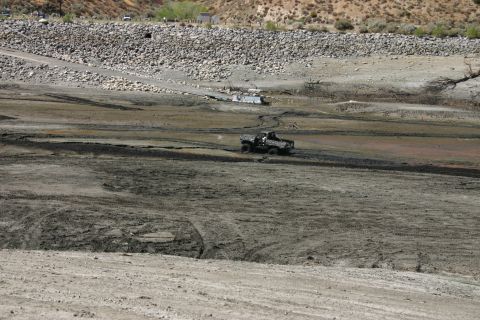 1991 Ford Bronco - An off-road vehicle navigates a desolate, muddy terrain, possibly a dried-up lakebed.