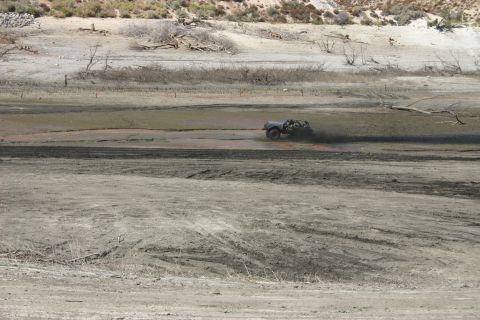 1991 Ford Bronco - An off-road vehicle navigates a muddy terrain, leaving a trail of dirt in its wake.