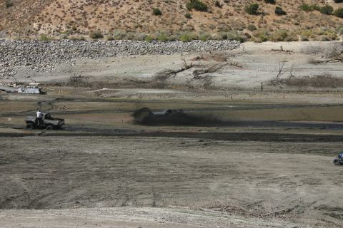 1991 Ford Bronco - Vehicles navigate a muddy terrain under a dry, rocky hillside.