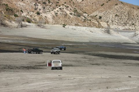 1991 Ford Bronco - Multiple off-road vehicles are gathered in a barren, dry landscape under a bright sky.