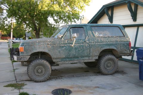 1991 Ford Bronco - This 1991 Ford Bronco is heavily covered in mud, suggesting recent off-road activity.