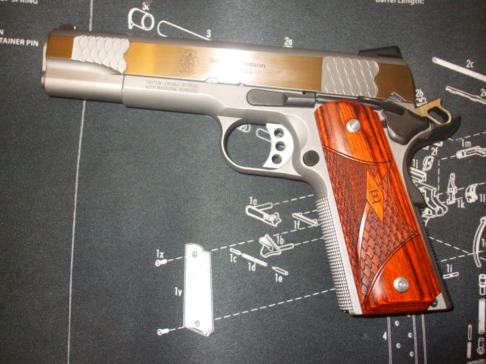 Pistol with gold slide and wood grips on a schematic mat