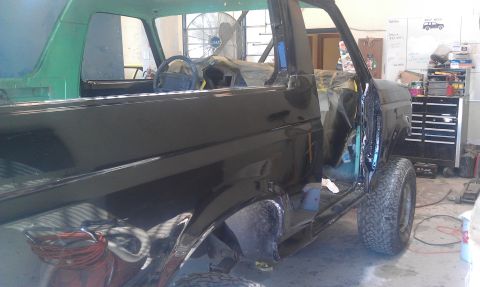1995 Ford Bronco - This 1995 Ford Bronco is in a workshop, with its doors open and interior covered, suggesting it is undergoing maintenance or restoration.