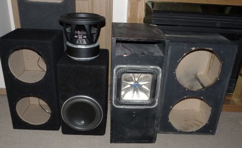 2006 Ford E350 - A collection of car audio subwoofers and speaker enclosures are displayed indoors.