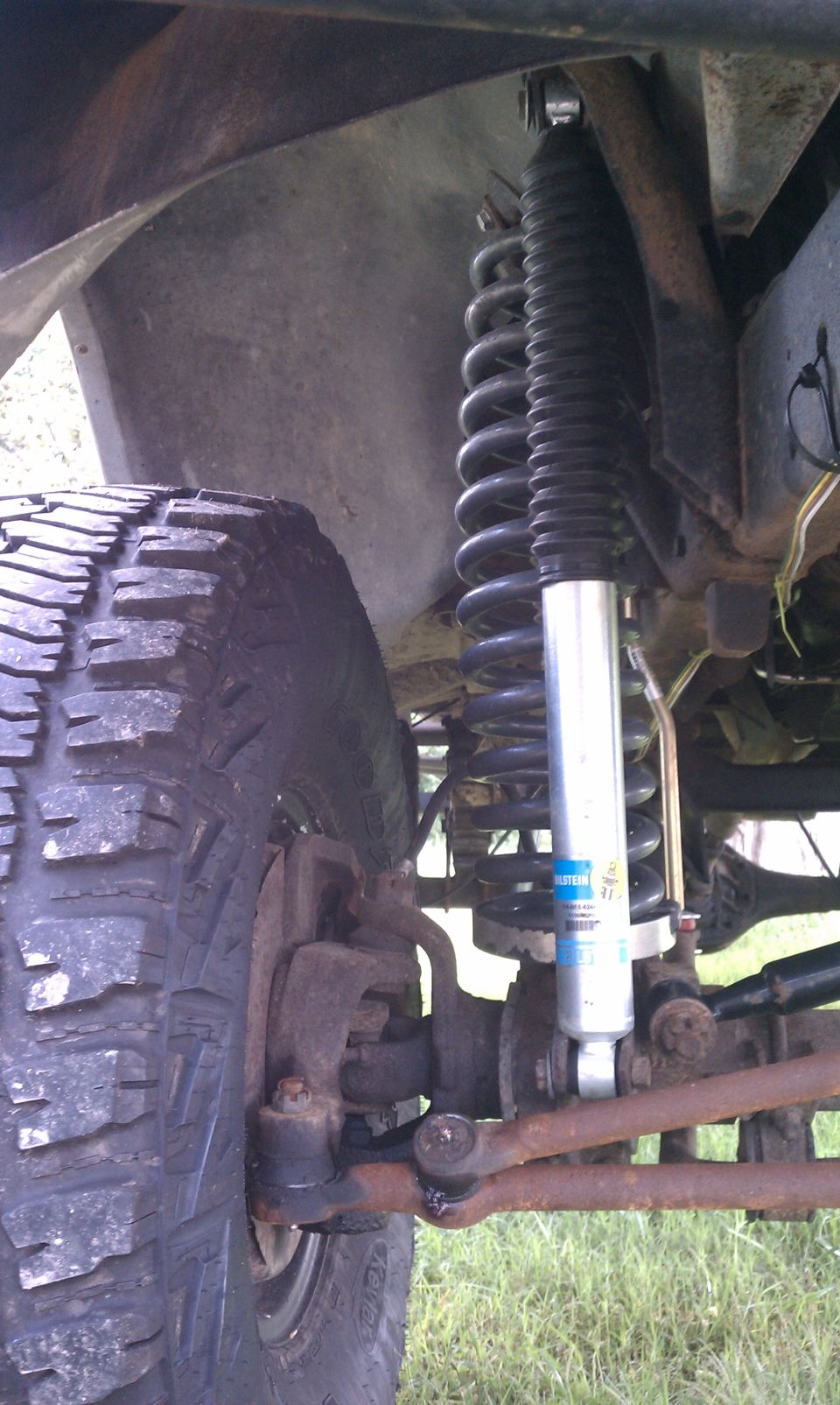 Close-up of a vehicle's front suspension with a large tire and a Bilstein shock absorber