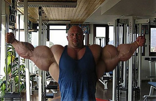Bodybuilder posing with arms spread in an indoor gym