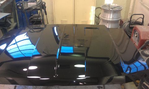 1995 Ford Bronco - A black hood with vents is displayed in a workshop setting.
