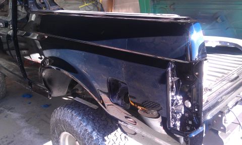 1995 Ford Bronco - This black Ford Bronco appears to be undergoing restoration, with visible body damage and incomplete paint.