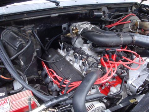 1989 Ford Bronco - The engine bay of a vehicle shows a V8 engine with red spark plug wires and an MSD ignition box.