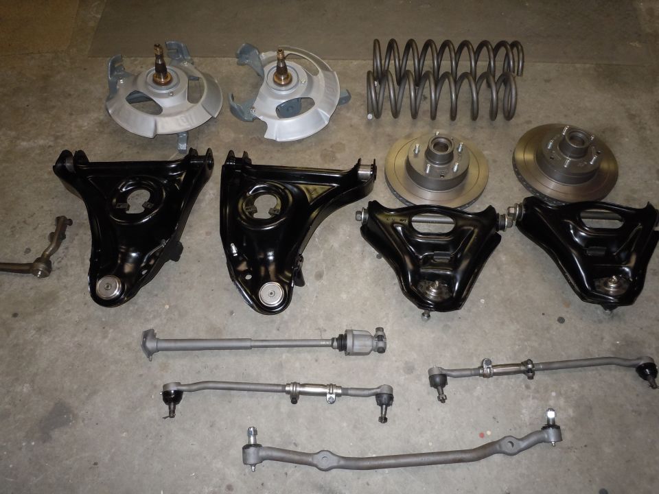 Assortment of black and silver suspension and steering components laid out on a concrete floor