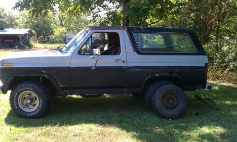 1985 Ford Bronco - Side view of a classic Ford Bronco, showing its two-tone paint job and off-road tires.