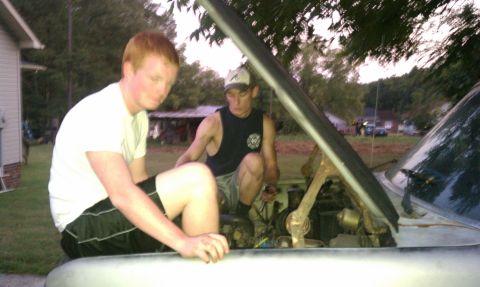1985 Ford Bronco - Two men are working on the engine of a car with the hood open.