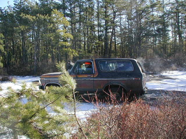 Side view of a rusty 1978 Ford Bronco in a snowy, wooded area