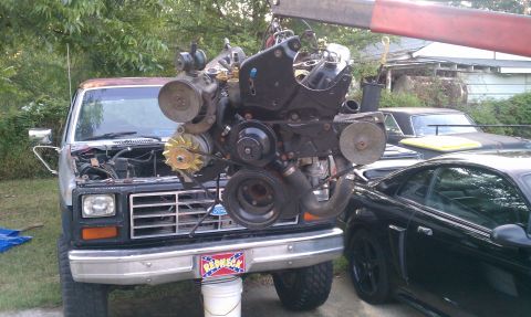 1985 Ford Bronco - Engine removal in progress on a 1985 Ford Bronco, with other vehicles present.