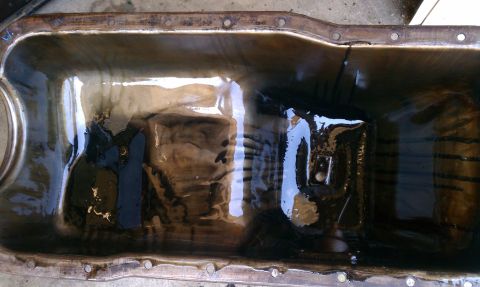 1985 Ford Bronco - This image shows the interior of an oil pan, filled with dark, sludgy oil, indicating potential maintenance needs.
