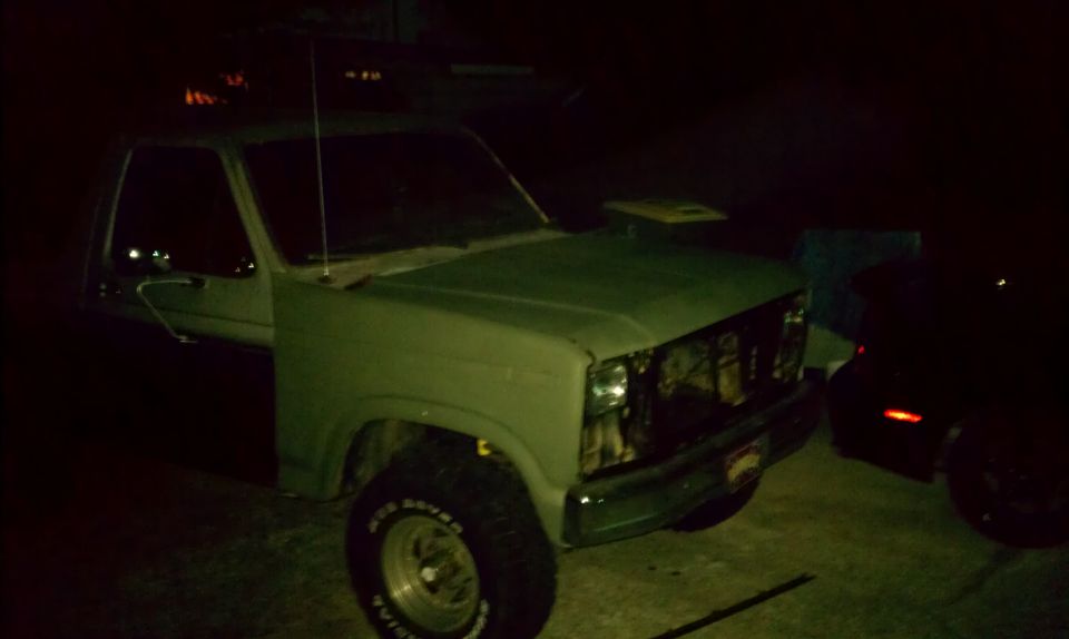 Green pickup truck with missing grille and headlights, viewed from the front-left