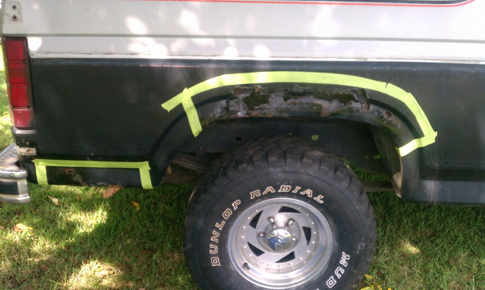 1985 Ford Bronco rear fender with masking tape around rusted area and wheel