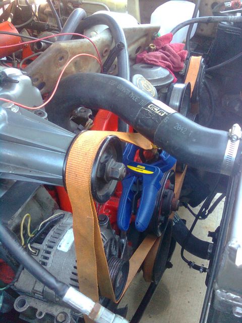 1984 Ford Bronco - Close-up of an engine bay showing a supercharger installation with an orange belt and blue clamp.