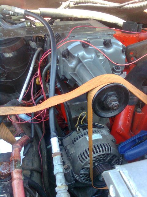 1984 Ford Bronco - Close-up view of an engine bay a supercharger, alternator, and drive belt, with visible wiring and hoses.