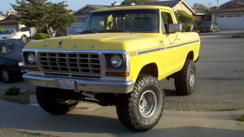 1978 Ford Bronco - A yellow 1979 Ford pickup truck is shown from a 3/4 front angle, modified with a lift kit and large tires.