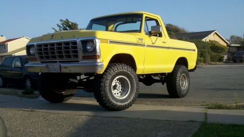1978 Ford Bronco - This yellow pickup truck has a lifted suspension and large off-road tires.