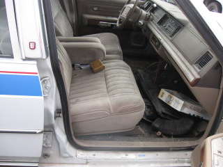 1991 Ford Crown Victoria LTD - The interior of a sedan is shown, with a focus on the seats and dashboard area. Some items are scattered on the floor.