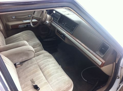 1991 Ford Crown Victoria LTD - The interior of a car shows velour seats and a dashboard with wood trim details.