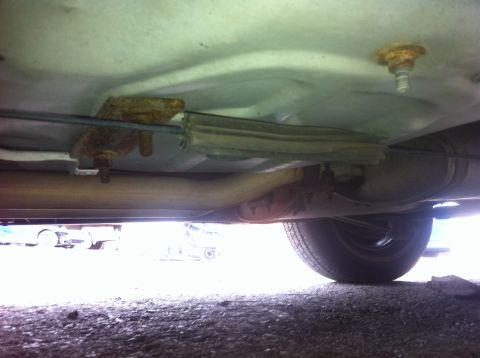 1991 Ford Crown Victoria LTD - Undercarriage view of a vehicle, showing the exhaust system and a tire. Other vehicles are visible in the background.