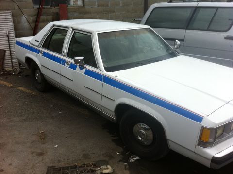1991 Ford Crown Victoria LTD - White 1991 Ford Crown Victoria LTD with a blue stripe is parked outside.