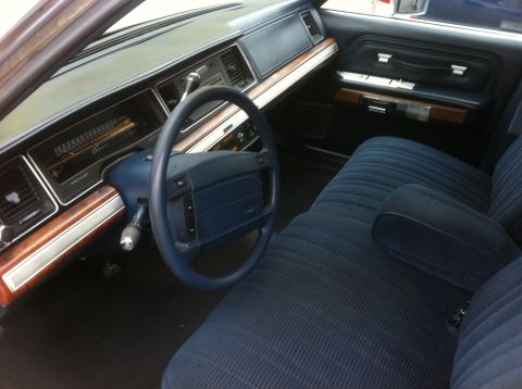 1991 Ford Crown Victoria LTD - The interior of a 1991 Ford Crown Victoria LTD features blue fabric seats and wood grain trim on the dashboard and doors.