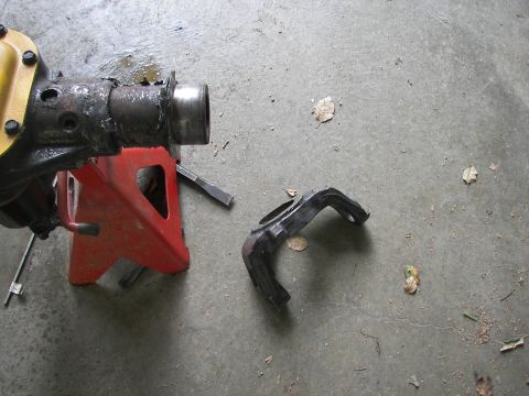 1988 Ford Bronco - Vehicle axle part and housing on jack stands, with a separate bracket on the floor.