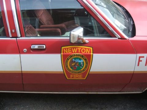 1991 Ford Crown Victoria LTD - The side of a red and white vehicle shows a Newton Fire Department emblem and part of the word 'FIRE'.