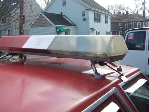 1991 Ford Crown Victoria LTD - Emergency light bar mounted on the roof of a red vehicle, with a white van in the background.