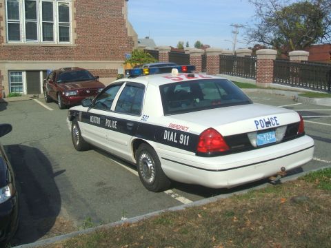 1991 Ford Crown Victoria LTD - A Newton Police car is parked in a lot next to a maroon sedan, with a building in the background.