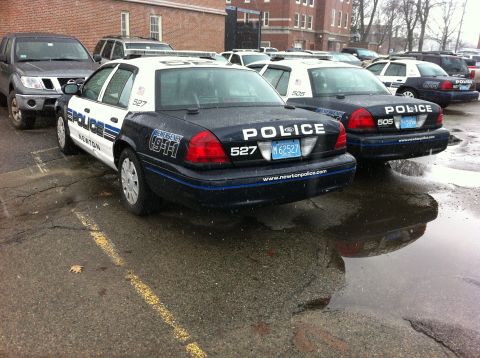1991 Ford Crown Victoria LTD - Two police cars, a 1991 Ford Crown Victoria LTD and another similar model, are parked in a lot on a rainy day.