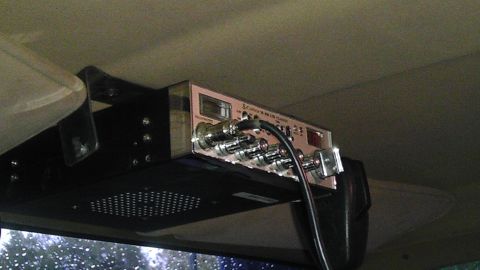 1989 Ford Bronco - A CB radio is mounted overhead inside a vehicle, with a view of trees through the windshield.