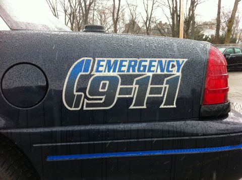 1991 Ford Crown Victoria LTD - Rear view of a 1991 Ford Crown Victoria LTD police car with "EMERGENCY 9-1-1" graphics on the body.