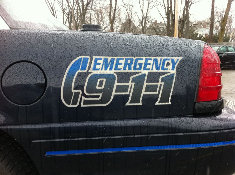 1991 Ford Crown Victoria LTD police car rear quarter panel showing "EMERGENCY 9-1-1" decal and part of taillight
