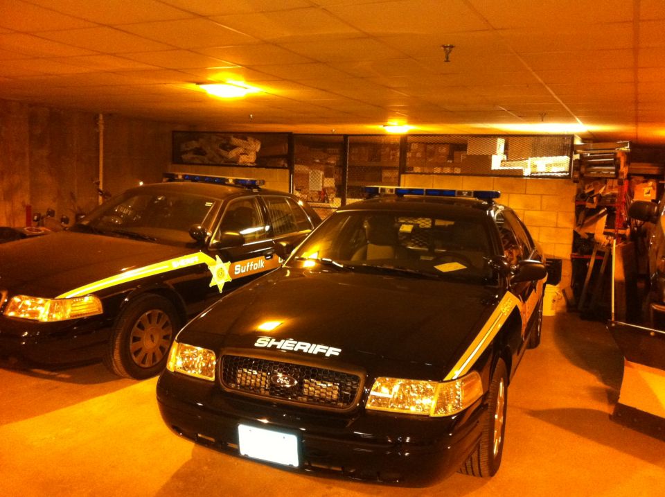 Front view of a black 2011 Ford Crown Victoria Sheriff's car with yellow stripe and light bar